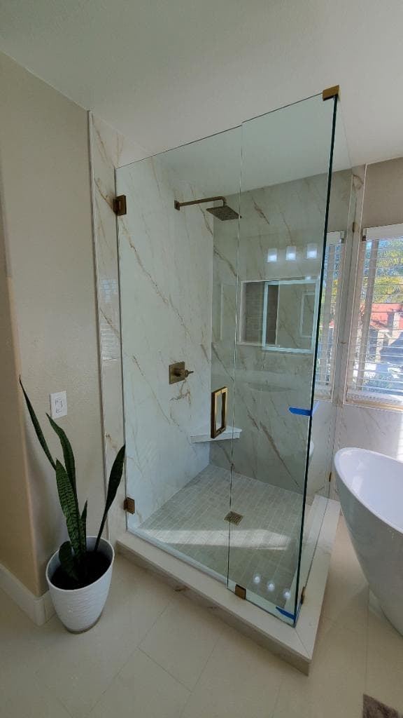 Luxury glass enclosed shower with marble-look porcelain tile in La Jolla home