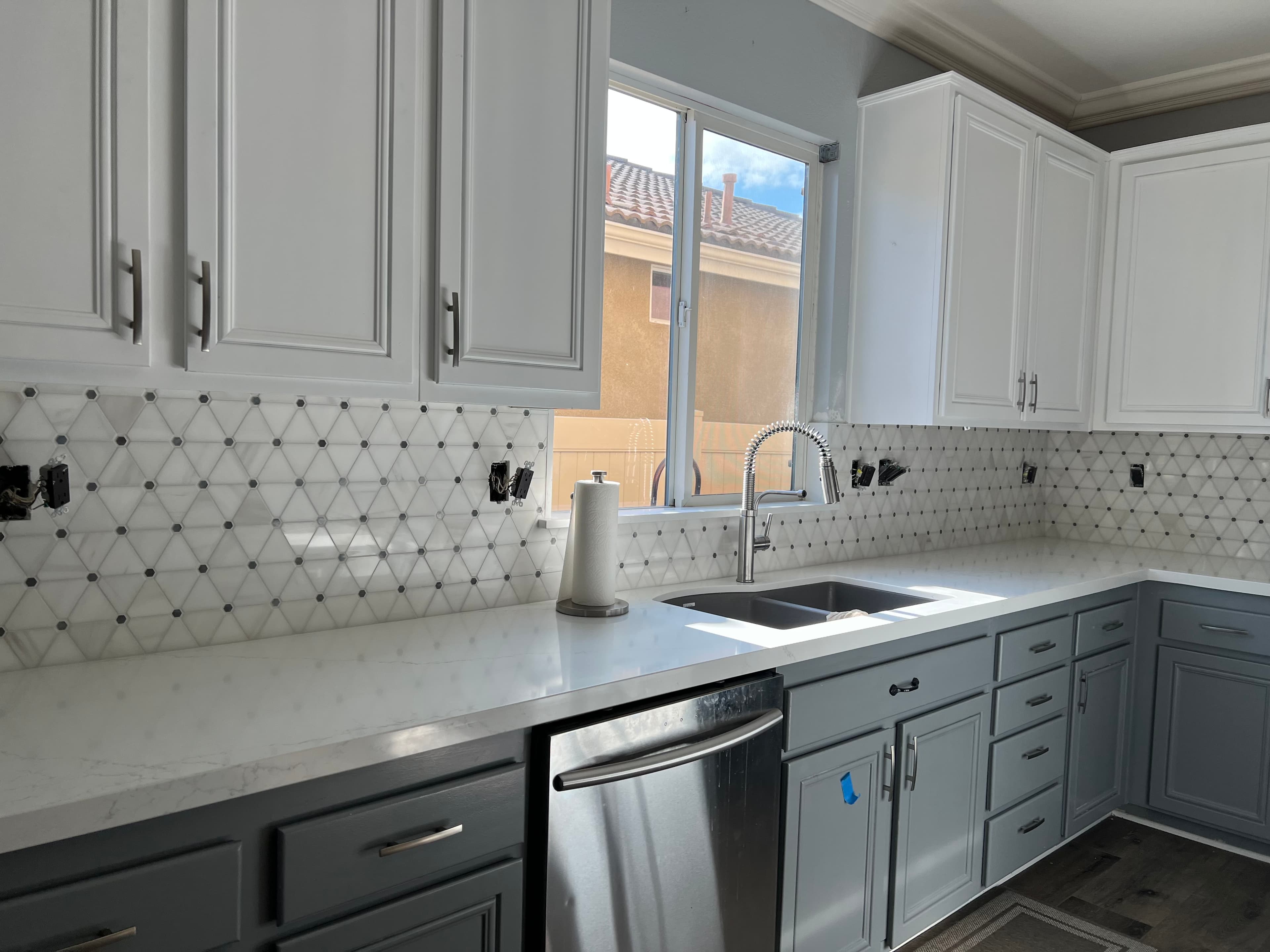 Two-tone kitchen with geometric tile backsplash and quartz countertops in Riverside