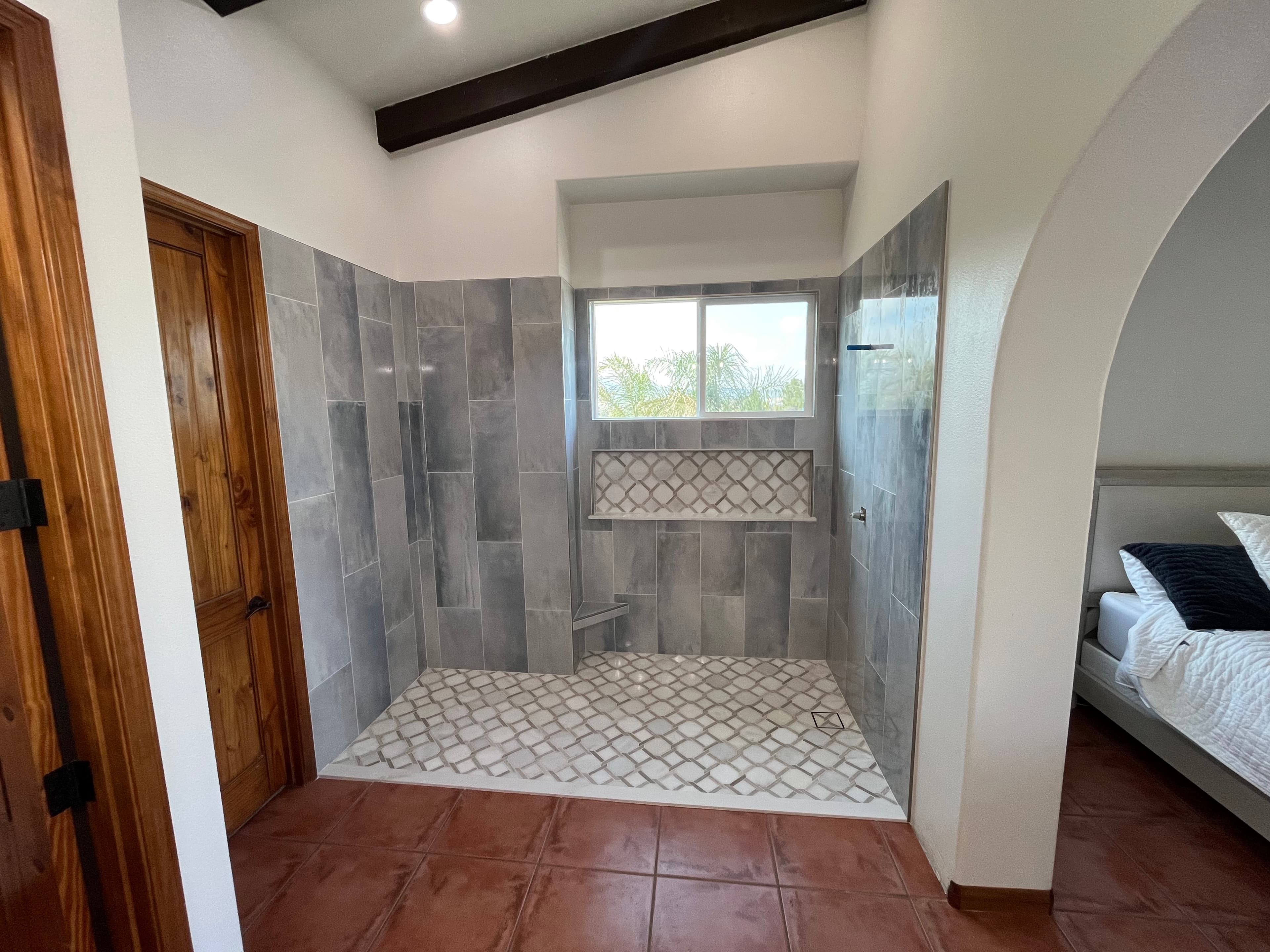 Open walk-in shower with decorative pattern floor tile in Newport Beach luxury bathroom