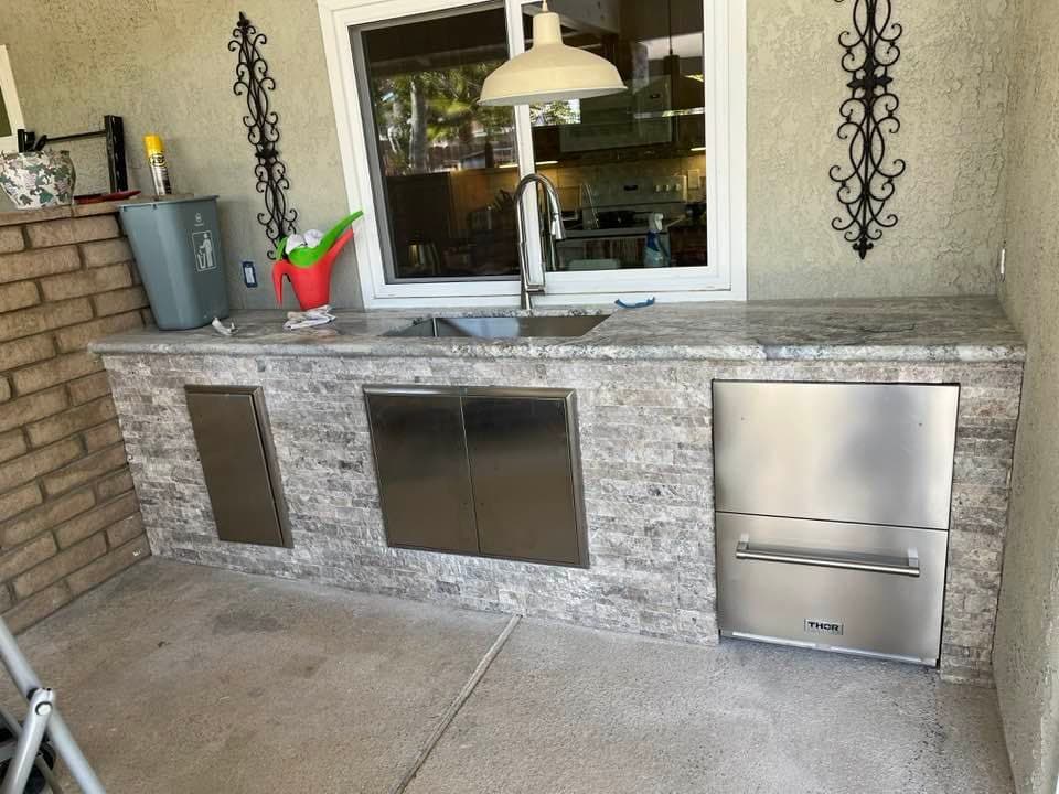 Outdoor BBQ kitchen island with tile and stone installation in Palm Springs backyard