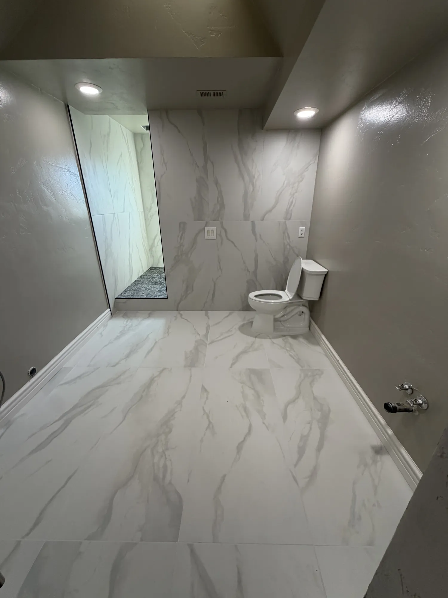 Menifee bathroom remodel with large format marble-look porcelain tile floor and full-height tiled shower wall
