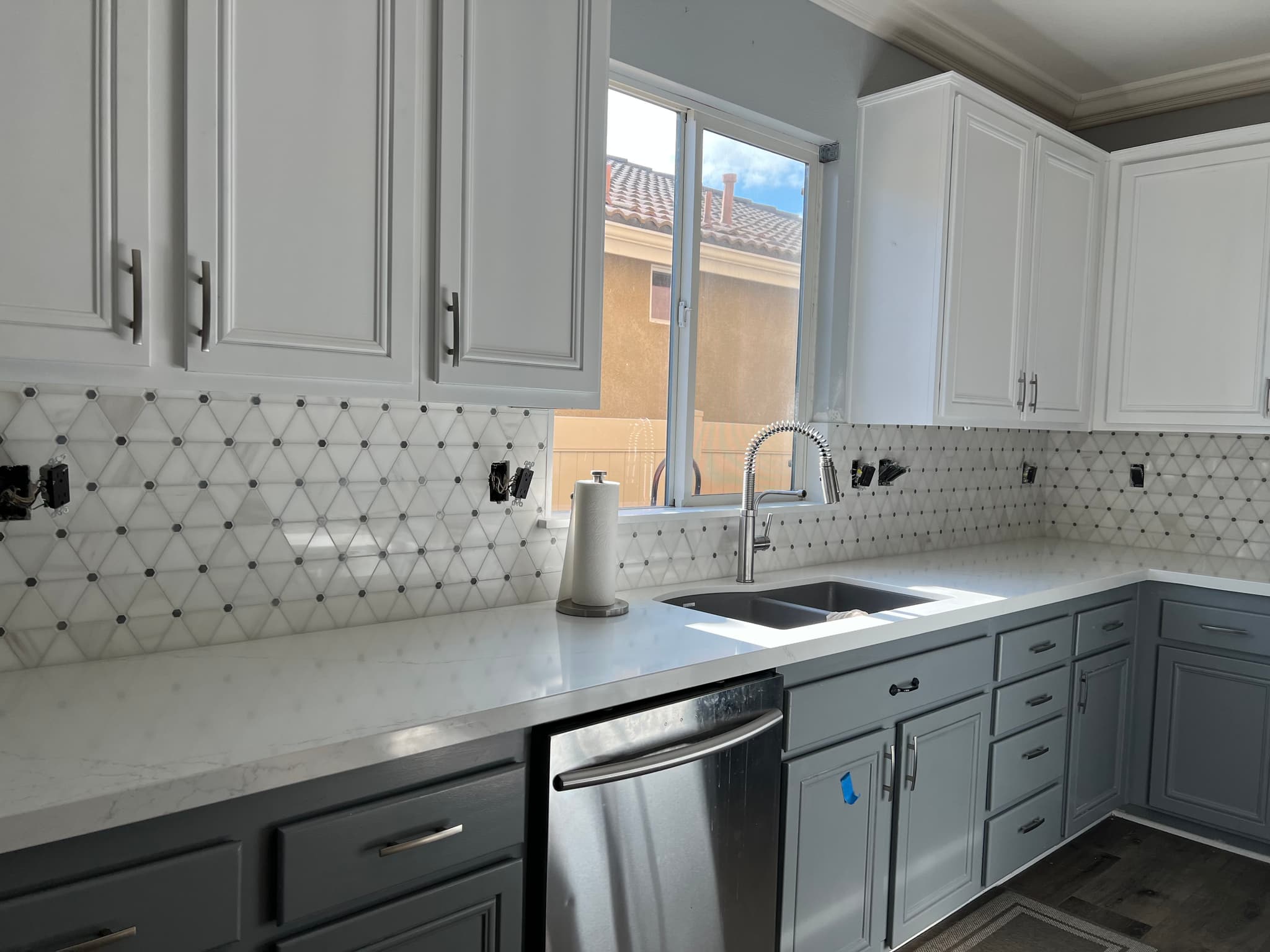 Two-tone kitchen with geometric tile backsplash and quartz countertops in Riverside