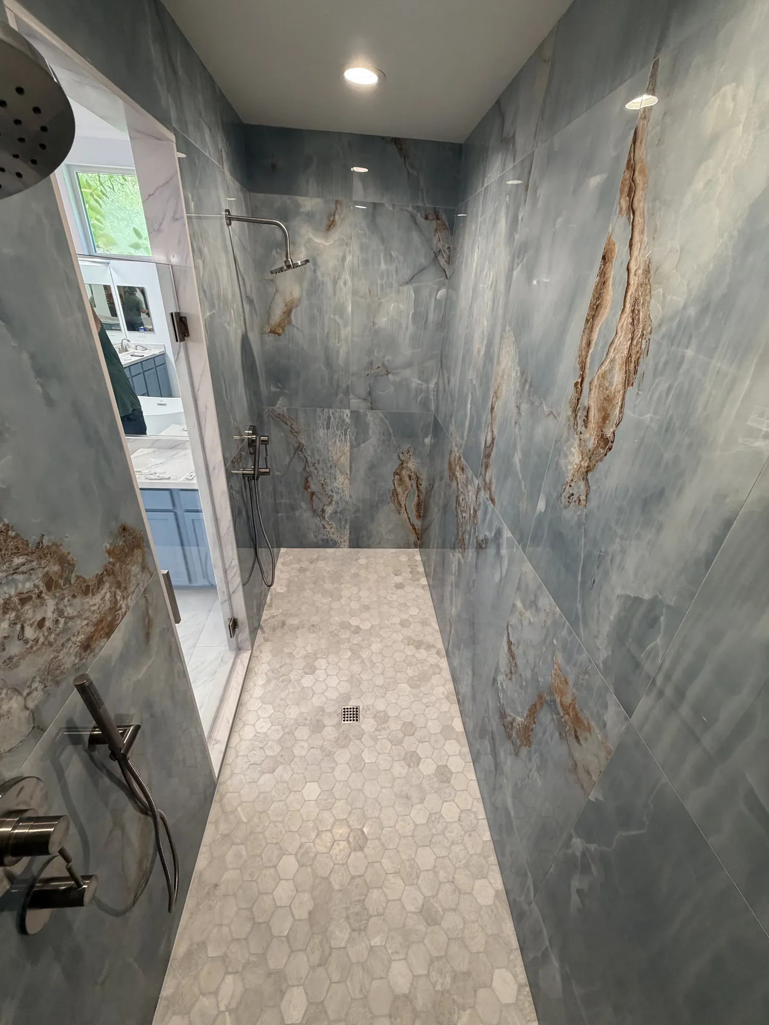 Book-matched blue and gold onyx-look porcelain shower walls with rain head and handheld fixtures in Murrieta
